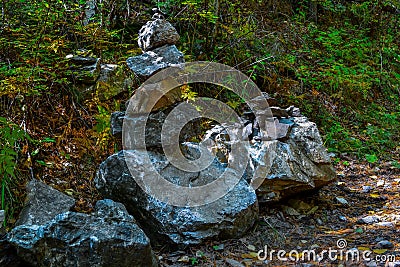 large gray rough colorful textured broken stones stand on top of each other with moss in green grass Stock Photo