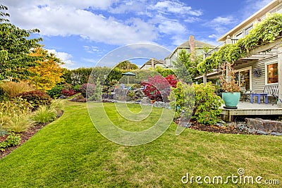 Large green fenced backyards with fall landscape and view of the deck. Stock Photo