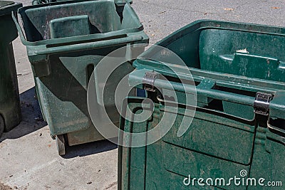 Large green trash cans, empty with lids open, curbside Stock Photo