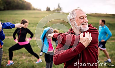 Large group of fit and active people doing exercise in nature, stretching. Stock Photo