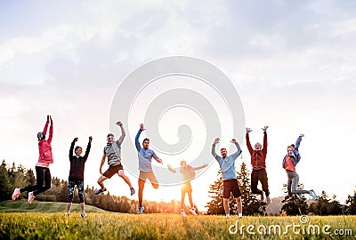 Large group of fit and active people jumping after doing exercise in nature. Stock Photo