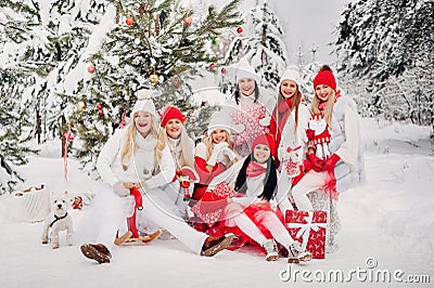 A large group of girls with Christmas gifts in their hands standing in the winter forest.Girls in red and white clothes with Stock Photo