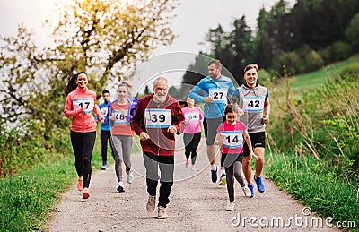 Large group of multi generation people running a race competition in nature. Stock Photo