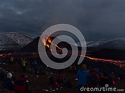 Large group of people watching a volcanic eruption at Fagradalsfjall with lava ejection, flowing streams of glowing lava. Editorial Stock Photo