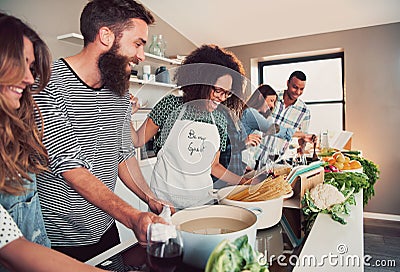 Large group of six friends cooking pasta at table Stock Photo