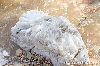 Large gypsum rock or stone surrounded by water. Big wet calcite washed in the river shore with lots of waves Stock Photo