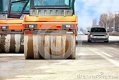 Large and heavy orange vibratory rollers move along the carriageway of the city road Stock Photo
