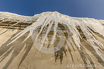 Large icicles formed on the roof during the thaw Stock Photo