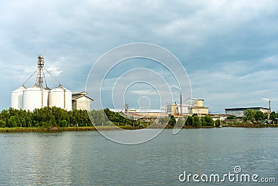 Large industrial factory and silo building at side coast of sea in evening with cloudy sky Stock Photo