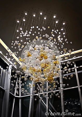 A large interior chandelier made of glass balls of white and green color. glass balls hanging from threads from the ceiling. Stock Photo