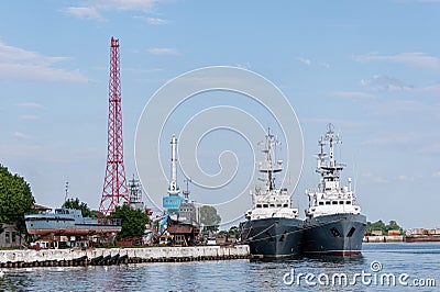 Large iron navy ships in shipyard for repair. Big crane in dockyard. Blue sea harbor. Ships anchorage Stock Photo