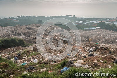 large landfill, with rows of garbage and recycling bins, surrounded by green landscape Stock Photo