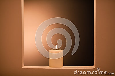 Large lighted candle on a shade background Stock Photo