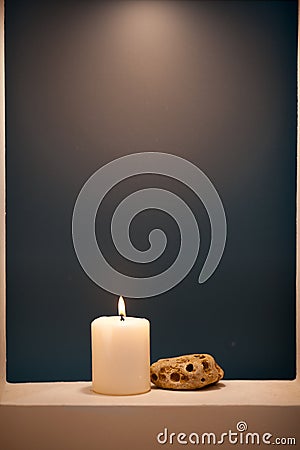 Large lighted candle on a shade blue background Stock Photo