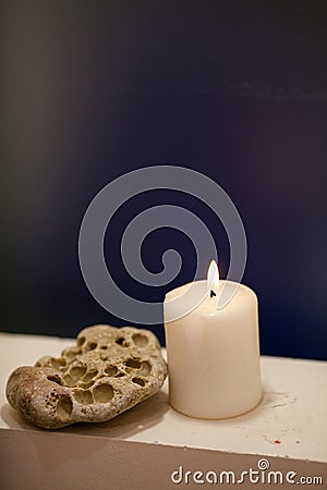 Large lighted candle on a shade blue background Stock Photo