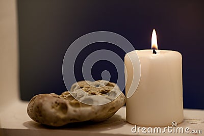 Large lighted candle on a shade blue background Stock Photo