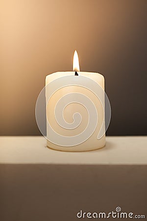 Large lighted candle on a shade contrast background Stock Photo