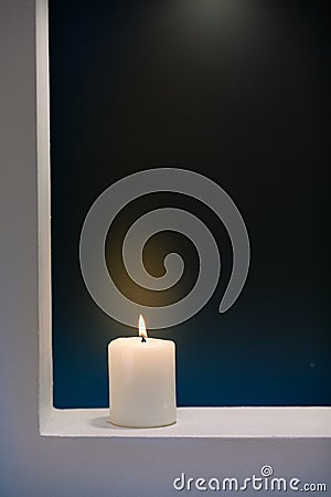 Large lighted candle on a shade contrast background Stock Photo