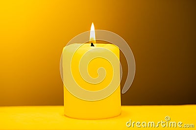 Large lighted candle on a warm yellow background Stock Photo