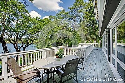 Large long balcony home exterior with table and chairs, lake view. Stock Photo