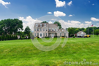 Large, luxurious, brick house with landscaping and a huge green lawn. Landscape on a summer sunny day under a blue cloudy sky Editorial Stock Photo