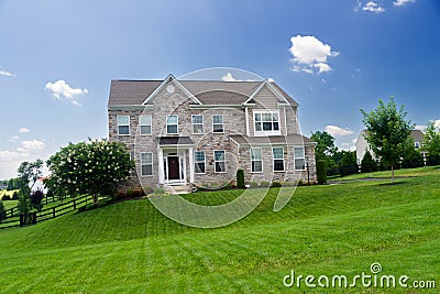 Large, luxurious, brick house with landscaping and a huge green lawn. Landscape on a summer sunny day under a blue cloudy sky Editorial Stock Photo