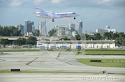 Large luxury commercial passenger private jet plane landing at Fort Lauderdale International Airport with cityscape in background Stock Photo