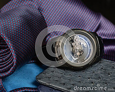 A large men`s watch against a pocket square, tie and ostrich leather wallets Stock Photo