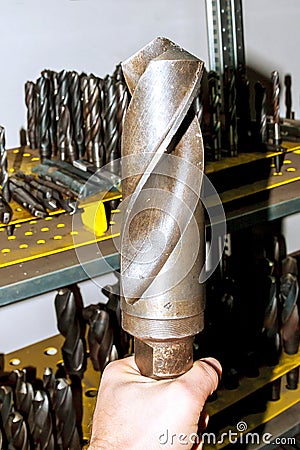 A large metal drill in the hand. Drilling and milling industry. Stock Photo
