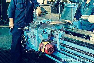 Large metal iron industrial turning and screw cutting machine for processing metal and parts with spare parts and a worker in a Stock Photo