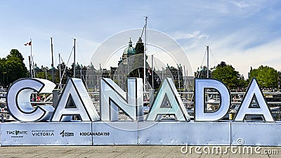 A large metal sign in block letters that spells out Canada at the inner harbor in Victoria, BC. Editorial Stock Photo