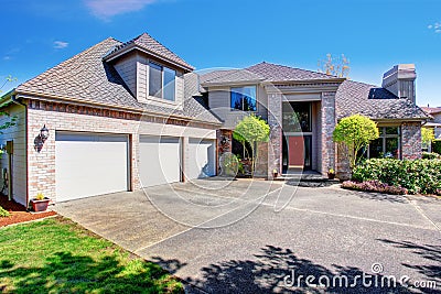 Large modern house with three garage spaces and concrete driveway. Stock Photo