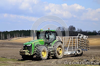 A large modern John Deere tractor tows a cultivator in a field Editorial Stock Photo