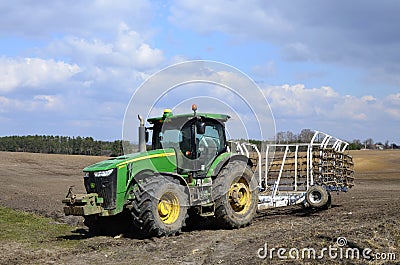 A large modern John Deere tractor tows a cultivator in a field Editorial Stock Photo