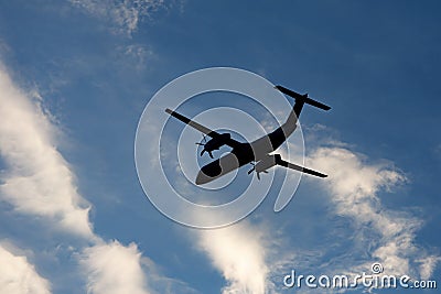 A large modern plane flies in the sky, a view from below from the ground to the belly of the aircraft. Stock Photo