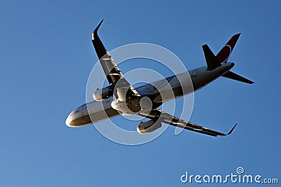 A large modern plane flies in the sky, a view from below from the ground to the belly of the aircraft. Stock Photo