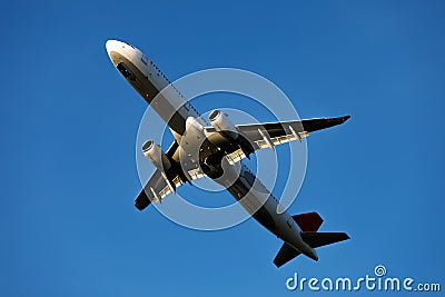 A large modern plane flies in the sky, a view from below from the ground to the belly of the aircraft. Stock Photo