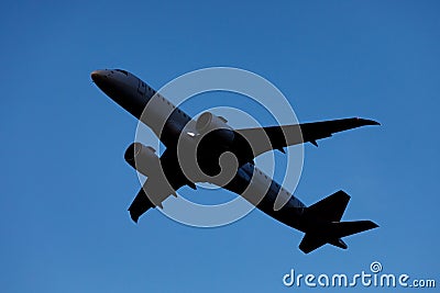 A large modern plane flies in the sky, a view from below from the ground to the belly of the aircraft. Stock Photo