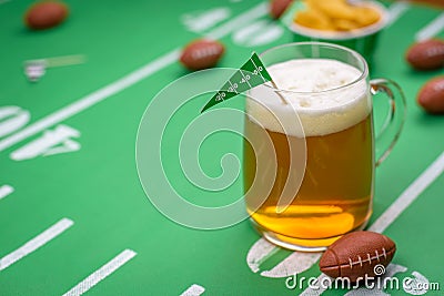 Large glass mug of cold beer on table with superbowl party decor Stock Photo