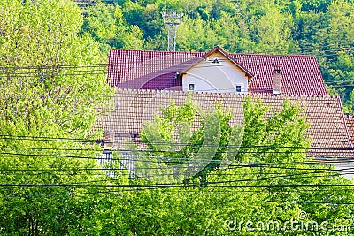 A large number of electrical wires in the background of the house and green hills Stock Photo