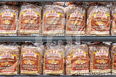 Oroweat brand plastic bags of 100% whole wheat bread for sale in a supermarket shelf Editorial Stock Photo
