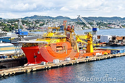 A large orange and yellow colored Offshore Construction Vessel OCV is in a dry dock of a shipyard and is being repaired Stock Photo