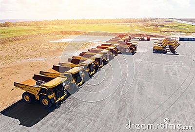 Large parking lot with big yellow mining truck, bulldozers for coal industry, ore and gold. Concept sale of industrial Stock Photo