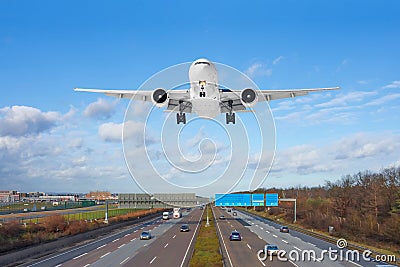 Large passenger aircraft landing over high speed highway Stock Photo