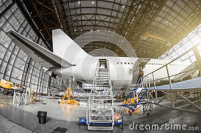 Large passenger aircraft on service in an aviation hangar rear view of the tail, gangway ladder entrance. Stock Photo
