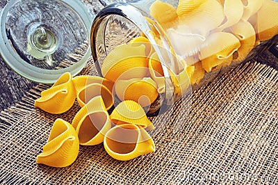 Large pasta shells in a glass jar on the background of jute Stock Photo