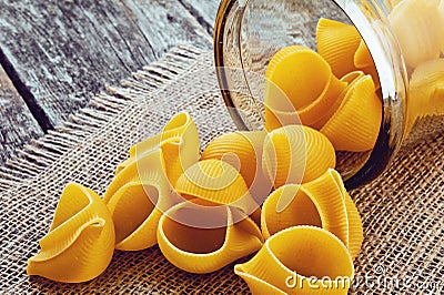 Large pasta shells in a glass jar on the background of jute Stock Photo