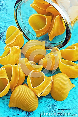 Large pasta shells in a glass jar on blue background Stock Photo