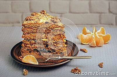 A large piece of homemade cake on a ceramic plate with nuts and mandarin Stock Photo
