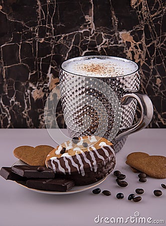 Large pimpled silver cup of coffee and cakes bisquits chocolate and coffee beans on the white reflective surface Stock Photo